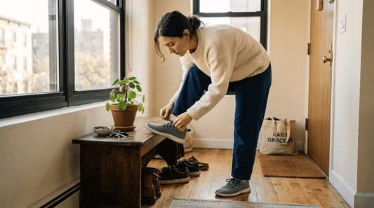 Woman lacing minimalist sneakers in bright entryway